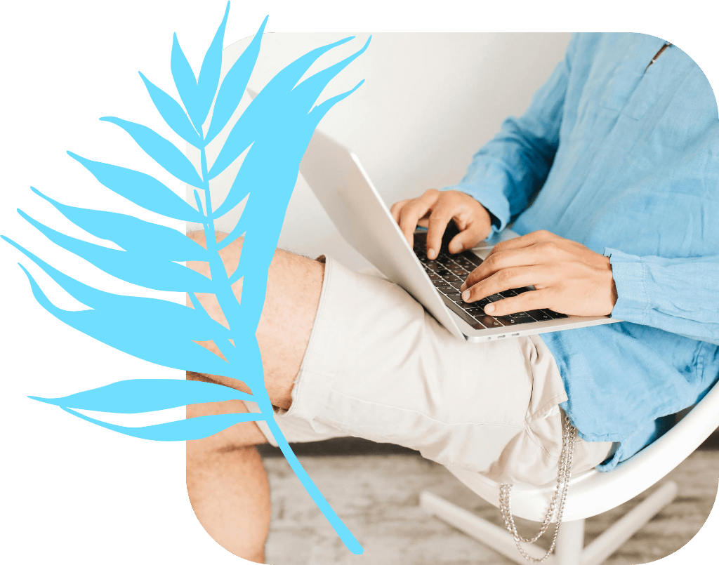 An Independent Travel Agent in a blue shirt and shorts sat with a laptop on his lap working