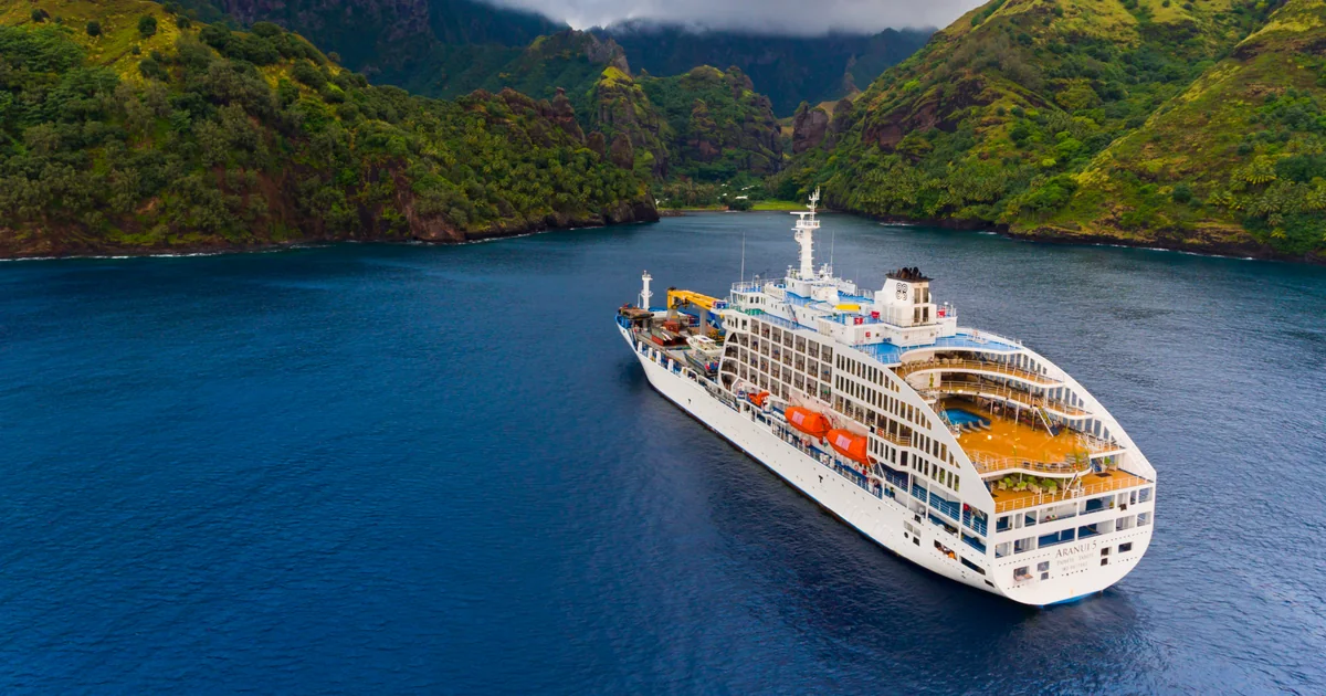 Aranui 5 cargo-passenger ship anchored off a Marquesas island with freight being unloaded